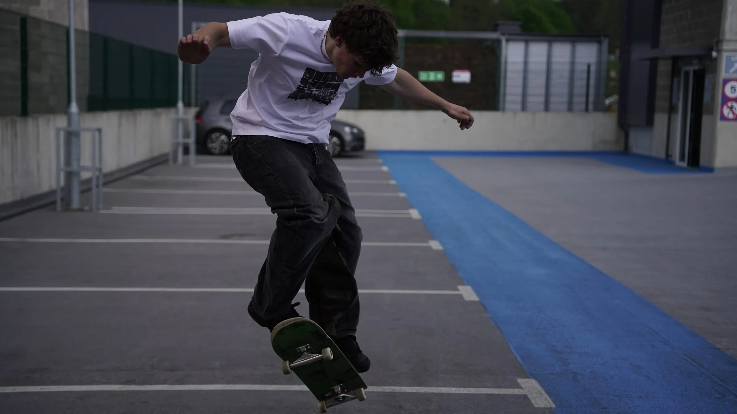 A skater mid-trick on an empty car park deck.