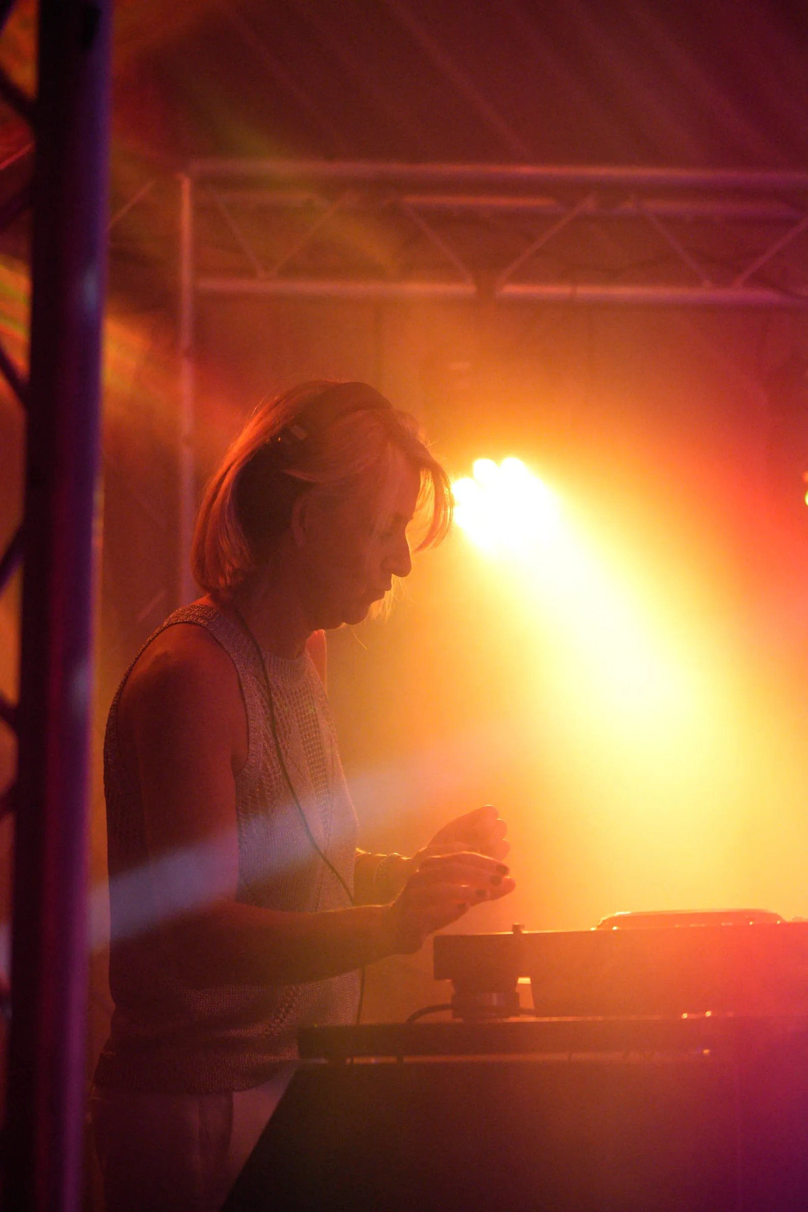 The DJ at the decks, backlit by an amber spotlight.
