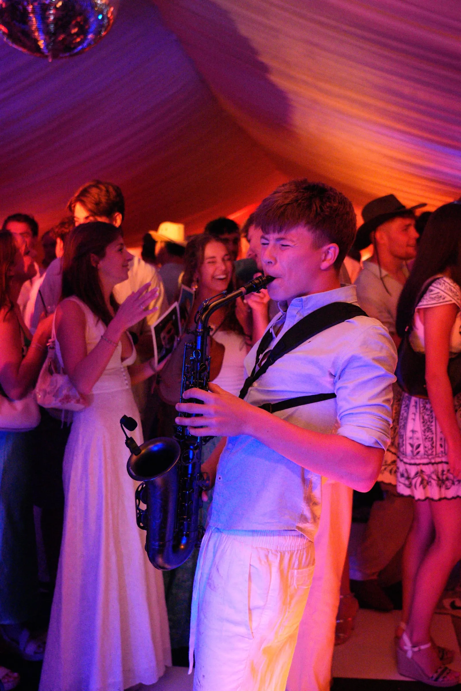 A saxophonist plays in the middle of the crowd.